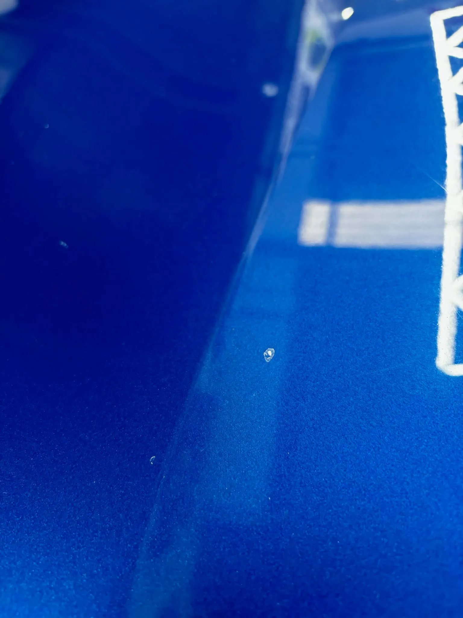 Detalle de pintura automotriz azul con reflejo de iluminación técnica