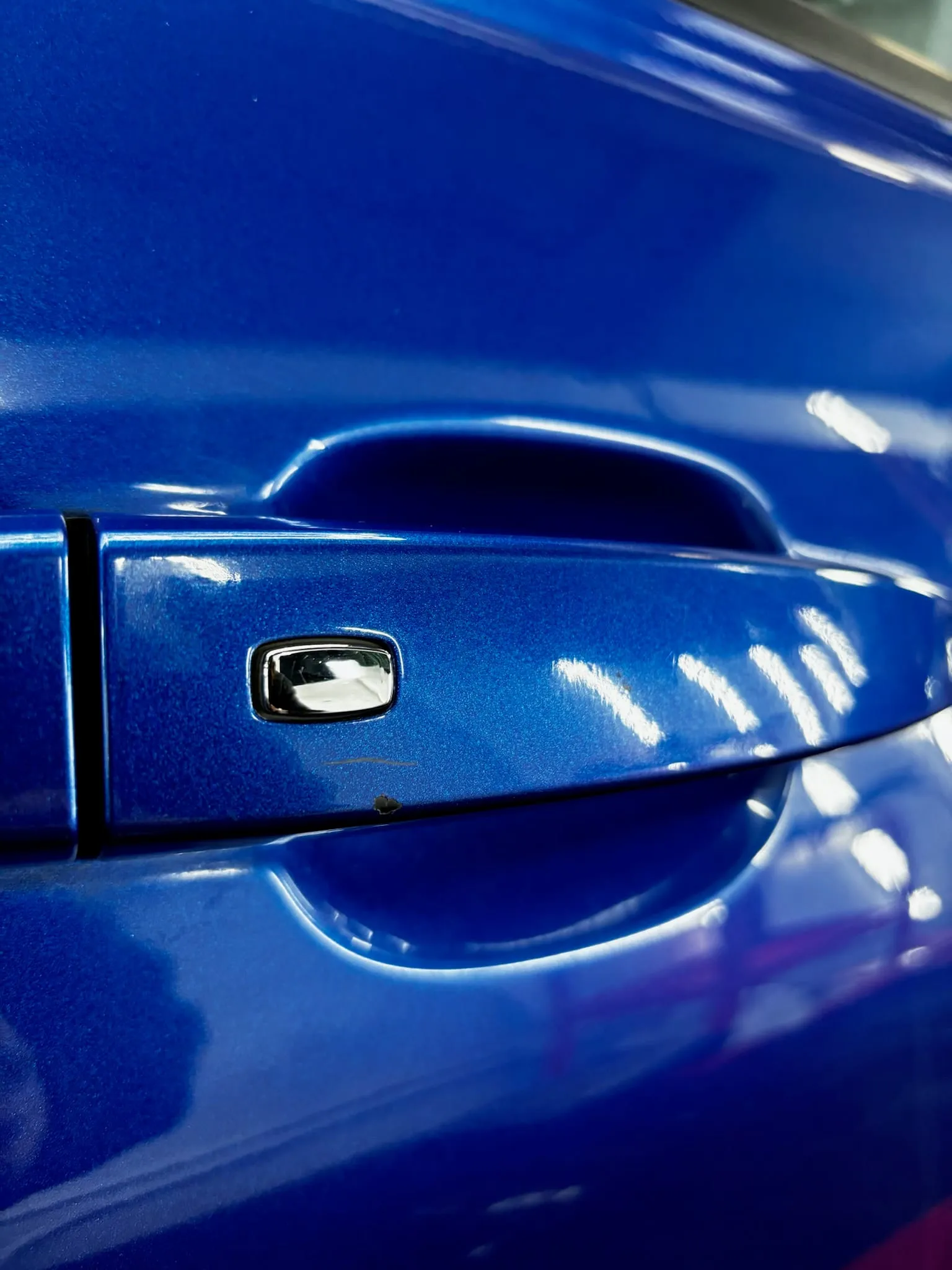 Detalle del acabado cerámico sobre la puerta de un Chevrolet Camaro azul