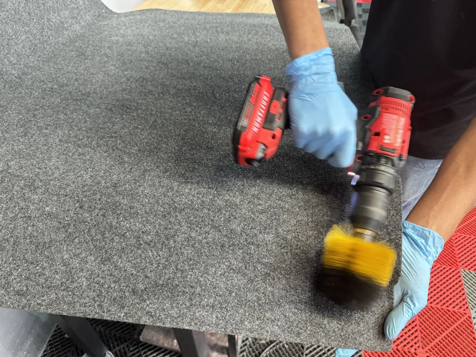 Técnico cepillando con brocha rotativa una alfombra desmontada